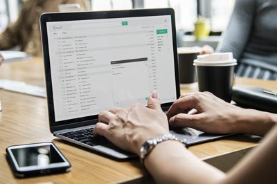 hand on laptop keyboard typing an email